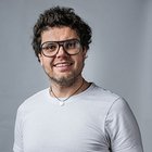 Fotografen und Filmer Lächelnder Mann mit Brille und weißen T-Shirt vor grauem Hintergrund