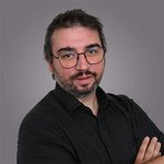 Das lvh-Team Mann mit Brille und Bart in schwarzem Hemd vor grauem Hintergrund