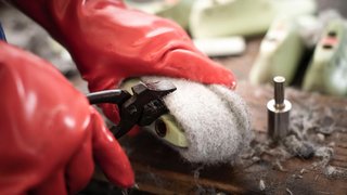 Junghandwerker Person entfernt Filzwolle mit Zange von Schuhsohle