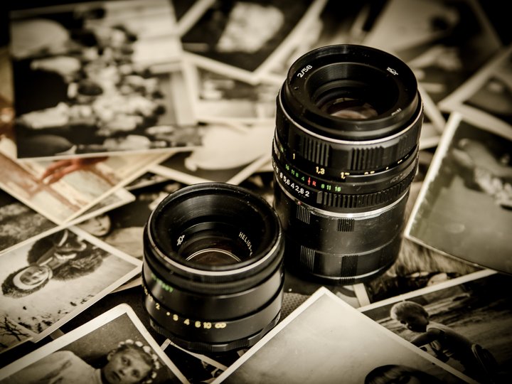 Fotografen und Filmer Zwei Kameraobjektive liegen auf einem Haufen alter Schwarzweiß-Fotos