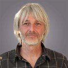 Bauwerksabdichter Porträt eines Mannes mit grauen Haaren und Bart vor grauem Hintergrund