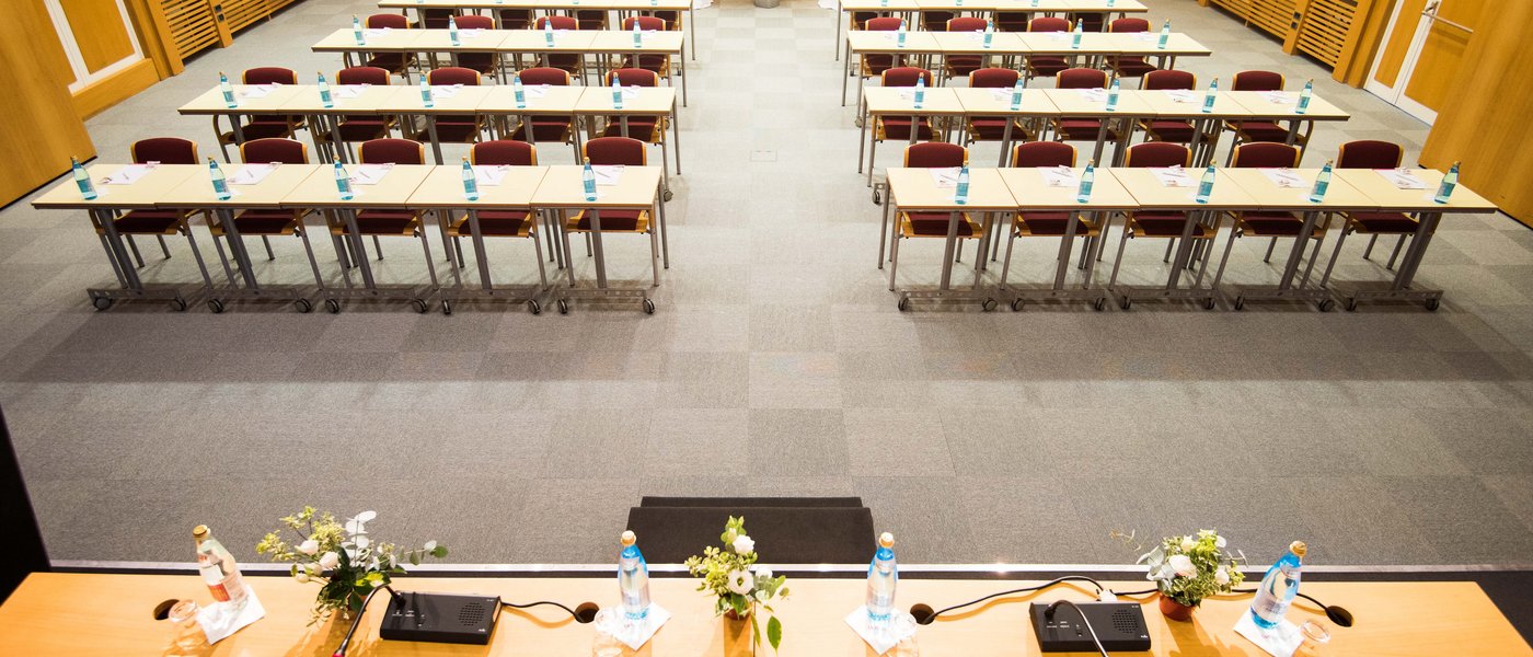 Vermietung Seminarräume Leerer Konferenzraum mit Tischen, Stühlen und Wasserflaschen vorbereitet für Meeting
