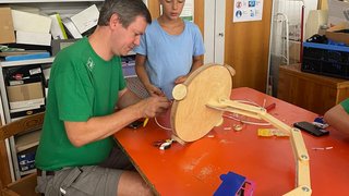 Junghandwerker Mann und Junge arbeiten an Holz-Mechanikprojekt am Tisch in Werkstatt