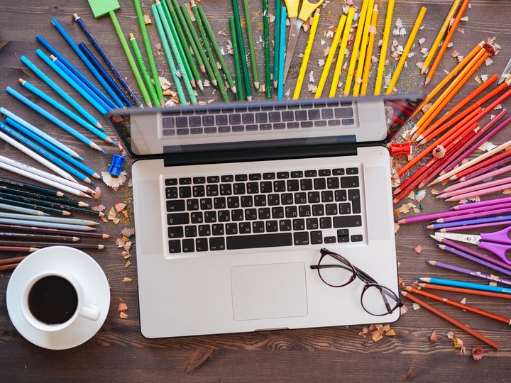 Mediendesigner Laptop auf Holztisch mit bunten Buntstiften, Kaffee und Brille