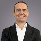 Steuerberatung, Buchhaltung und Lohnabrechnung Porträt eines lächelnden Mannes mit weißem Hemd und dunklem Sakko vor grauem Hintergrund