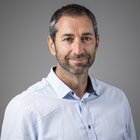 Steuerberatung, Buchhaltung und Lohnabrechnung Mann mit grau meliertem Haar und blauem Hemd vor grauem Hintergrund