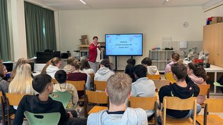 Junghandwerker Lehrerin stellt Schülern in einem Klassenzimmer Handwerksberufe vor