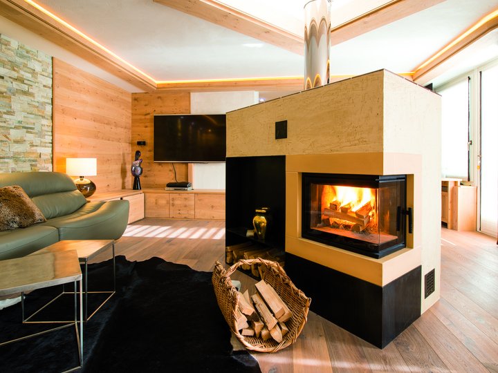 Hafner Gemütliches Wohnzimmer mit Kamin, grünem Sofa und moderner Holzverkleidung