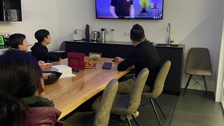 Junghandwerker Personen schauen eine Präsentation an einem Bildschirm in einem Besprechungsraum.