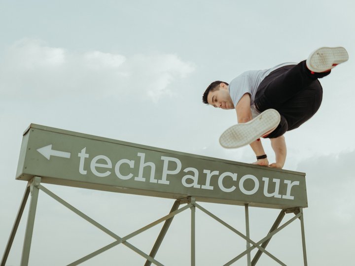 Digitale Lösungen Mann macht Parkour-Sprung über TechParcour-Schild
