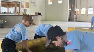 Junghandwerker Kinder lernen in einer Halle mit Holzboxen und Werkzeugen