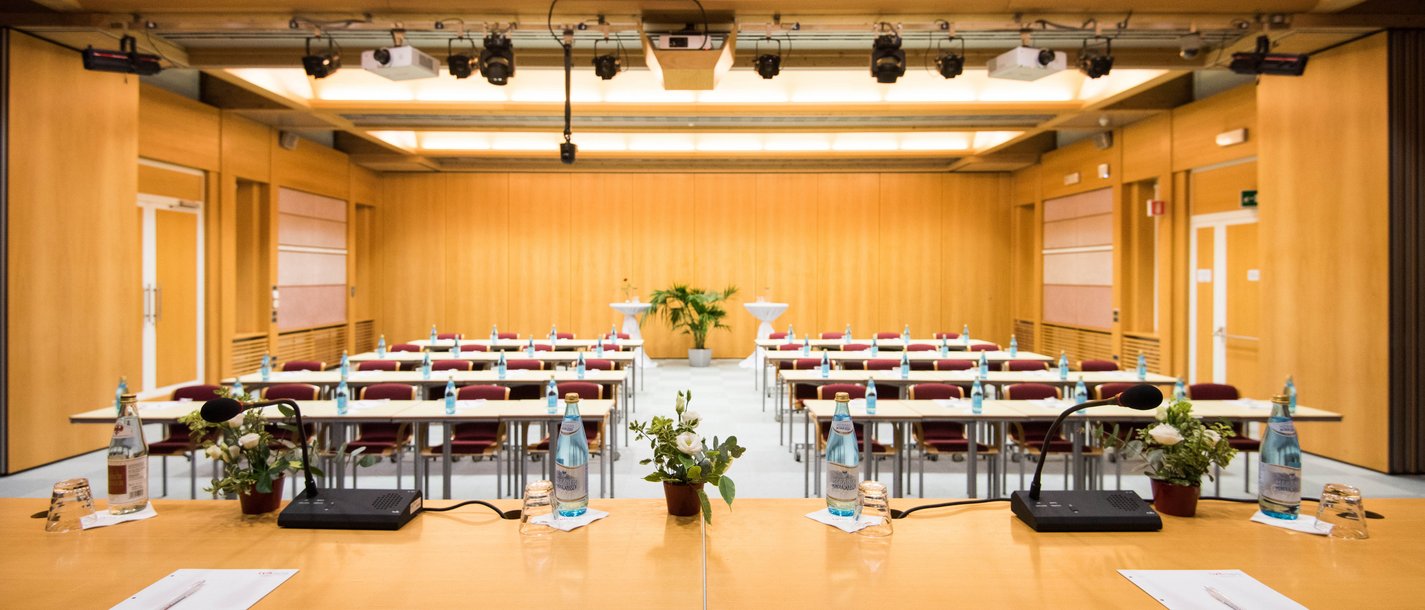 Vermietung Seminarräume Leerer Tagungsraum mit Rednerpult, Mikrofonen und Flaschenwasser