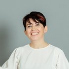 Frauen im Handwerk Lächelnde Frau mit kurzen dunklen Haaren vor grauem Hintergrund