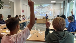 Junghandwerker Schüler heben die Hand in einem Klassenzimmer während einer Präsentation