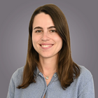 Förderungen im Bereich Produktentwicklung und Innovation Porträt einer lächelnden jungen Frau mit braunen Haaren vor grauem Hintergrund