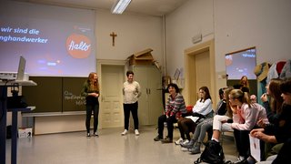 Junghandwerker Gruppe von Menschen in einem Klassenzimmer hört Vortrag vor einer Leinwand