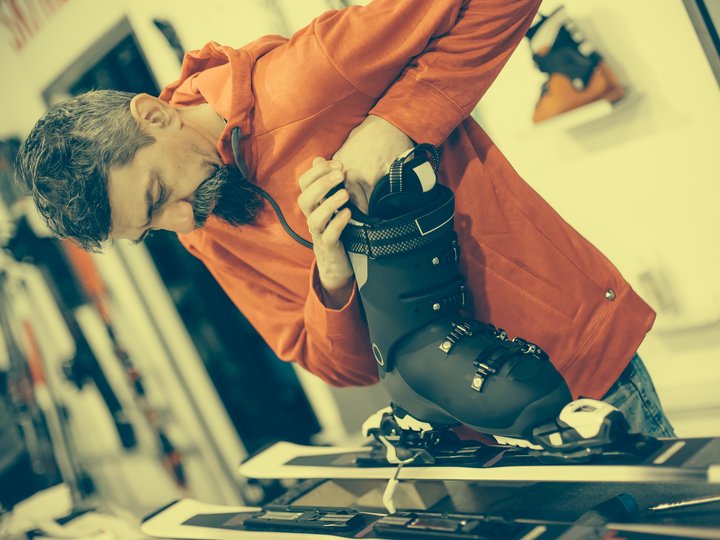 Sportgerätetechniker Mann stellt Skischuh auf Skier in einem Sportgeschäft ein