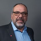 Sportgerätetechniker Porträt eines älteren Mannes mit Brille und Bart vor grauem Hintergrund