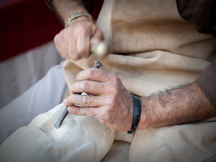 Steinmetze und Steinbildhauer Steinmetz bearbeitet mit Hammer und Meißel eine Skulptur