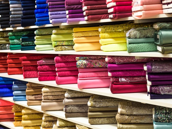 Maßschneider Bunte Stoffe ordentlich gefaltet und nach Farben im Ladenregal sortiert