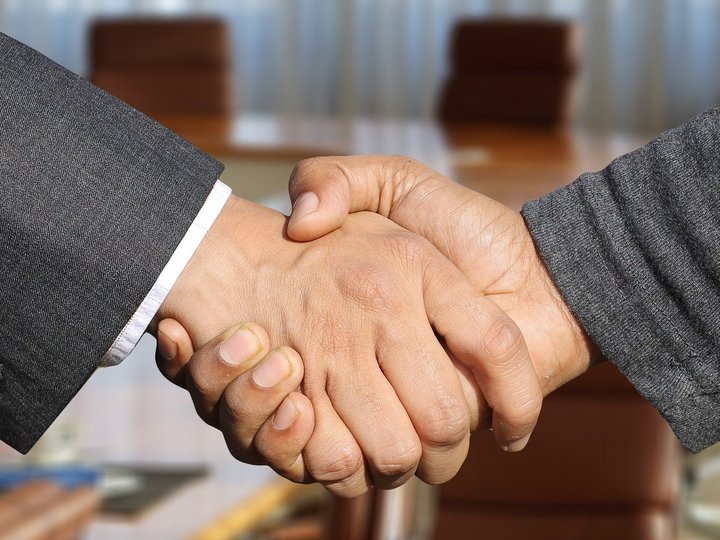 Datenschutz Zwei Personen geben sich die Hand in einem Büro