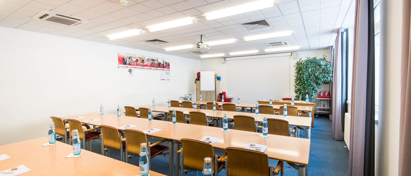 Vermietung Seminarräume Konferenzraum mit Tischen, Stühlen, Flaschen und Schreibmaterialien