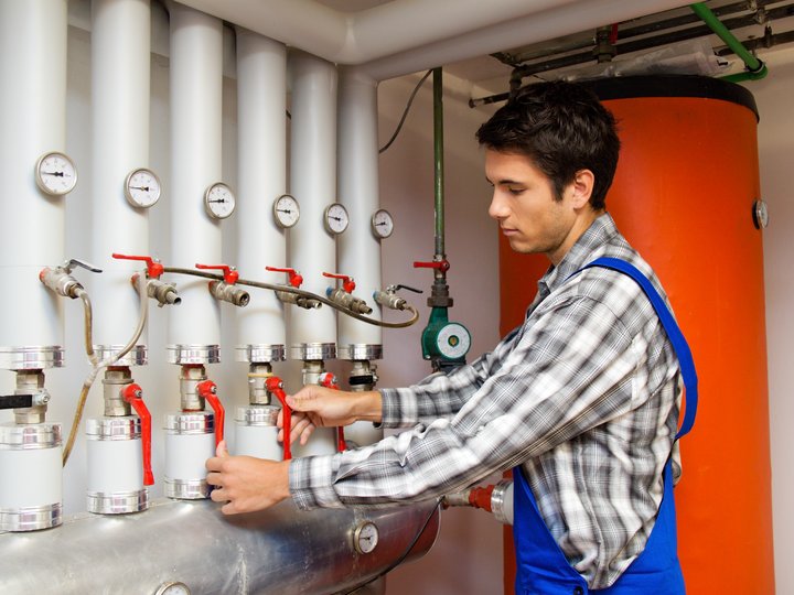 Feuerungstechniker Techniker bedient Ventile und Druckmesser an Heizungsanlage
