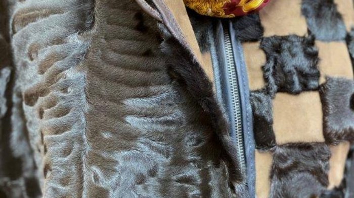 Kürschner Nahaufnahme eines Pelzmantels mit Muster und Schal in Rot und Gold