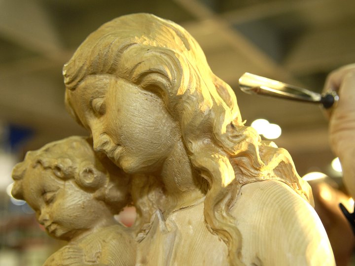 Holzschnitzer Hand schnitzt detaillierte Holzfigur von Mutter mit Kind