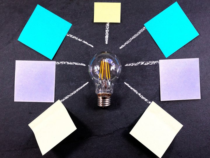 Workshops Glühbirne mit verbundenen Haftnotizen auf Tafel für Ideensammlung