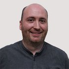 Maschinenbaumechaniker und Werkzeugmacher Porträt eines lächelnden, glatzköpfigen Mannes mit kurzer Gesichtsfrisur