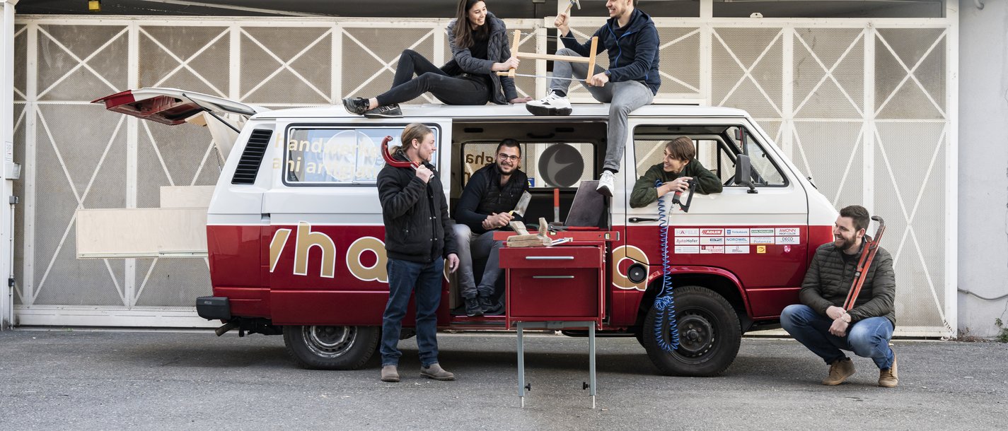 Junghandwerker Gruppe von sechs Handwerkern mit Werkzeug neben und auf einem roten Transporter