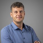 Das lvh-Team Mann mit blauem Hemd und verschränkten Armen vor grauem Hintergrund