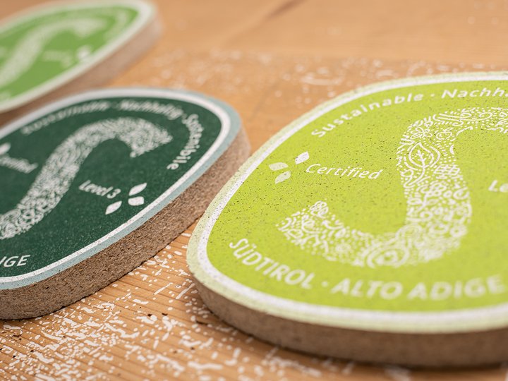 Nachhaltiges Handwerk Nachhaltigkeitssiegel aus Südtirol mit grünen und dunklen Farben auf Holzoberfläche
