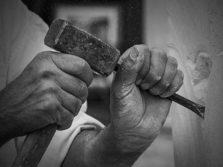 Verzierungsbildhauer Hände eines Steinmetzes beim Bearbeiten von Stein mit Hammer und Meißel