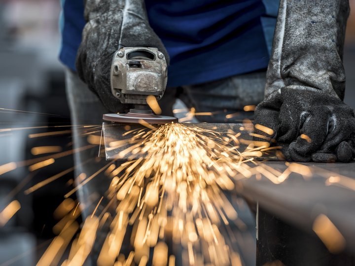 Schmiede und Schlosser Person schleift Metall mit Winkelschleifer und Funken fliegen