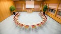 Vermietung Seminarräume Konferenzraum mit Stühlen im Halbkreis vor einem Tisch und einer Leinwand