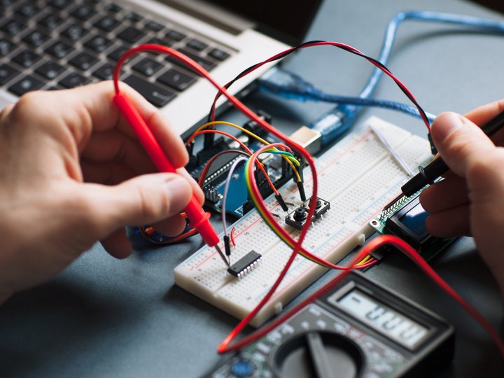Elektromechaniker Person misst mit Multimeter auf einem Steckbrett mit elektronischen Bauteilen