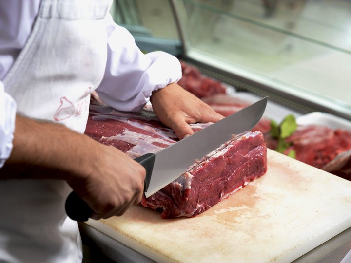 Metzger Metzger schneidet rohes Rindfleisch auf einem Schneidebrett