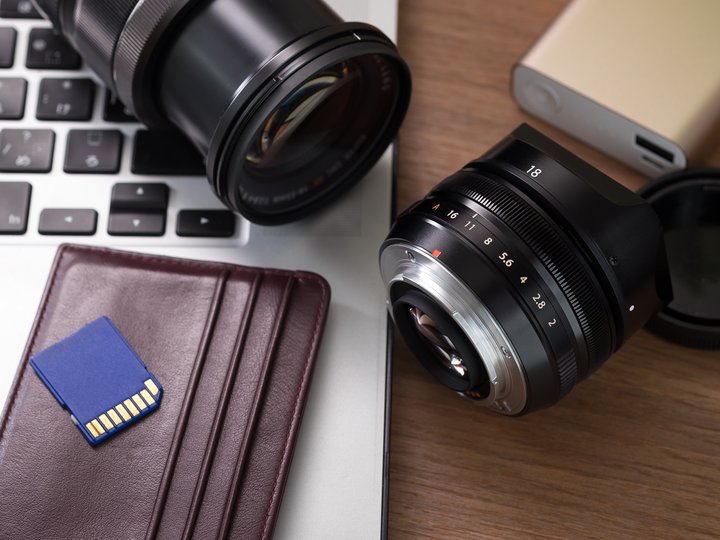 Fotografen und Filmer Kameralinsen, SD-Karte, Laptop und Portemonnaie auf Holztisch