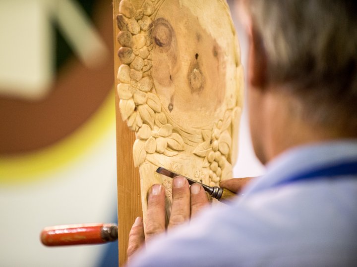 Holzschnitzer Handwerker schnitzt florale Muster in Holz mit Stechbeitel