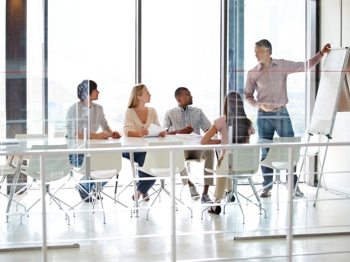 Unternehmensentwicklung Team mit 4 Personen in Besprechung, eine Person präsentiert an Flipchart im Büro