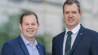 Berufsbildung Zwei Männer in Anzügen lächelnd vor einem Gebäude