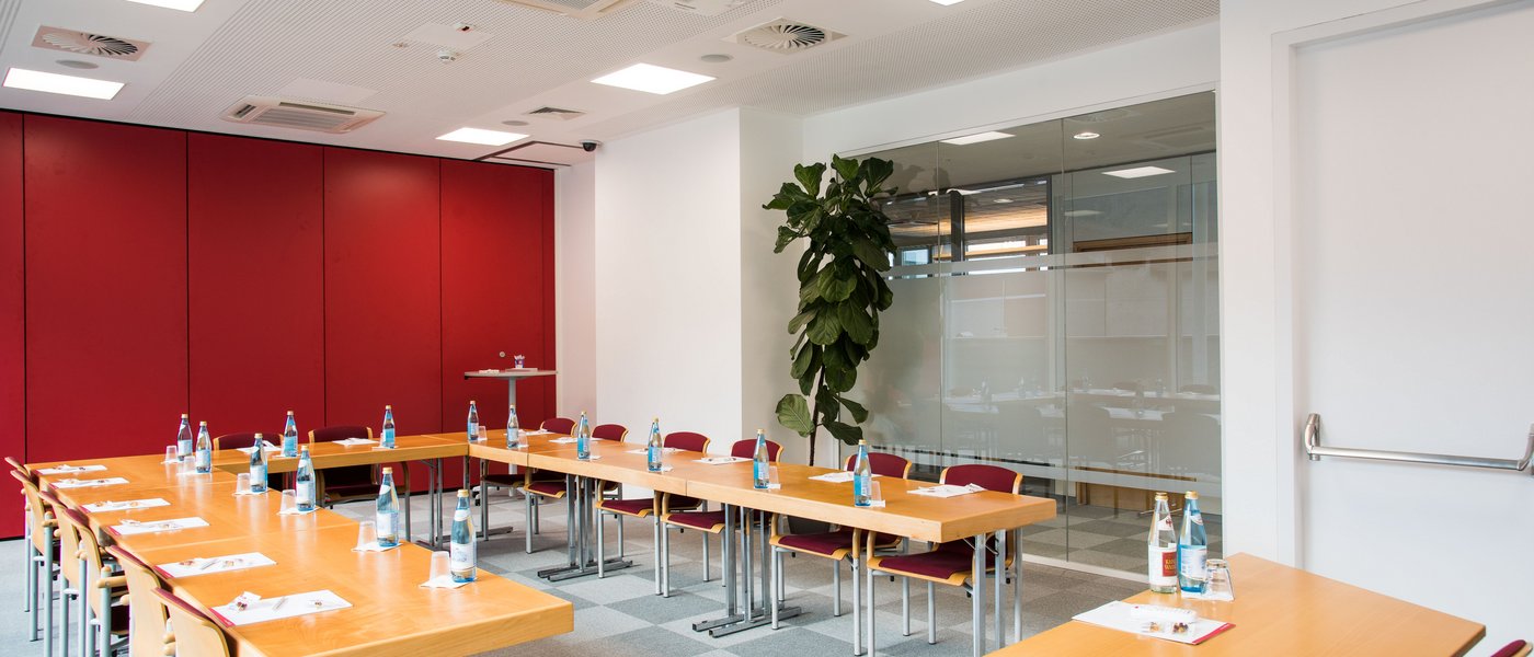 Vermietung Seminarräume Moderner Konferenzraum mit U-förmigem Holztisch und Flaschen Wasser