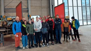 Junghandwerker Gruppe junger Menschen und zwei Erwachsene in einer Industriehalle