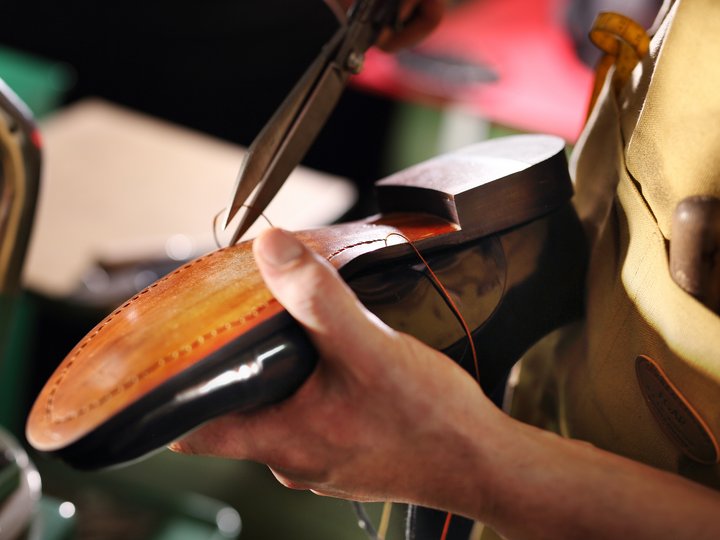 Schuhmacher Handfertiger näht die Ledersohle eines hochwertigen Schuhs mit einer Zange