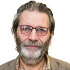 Glaser Porträt eines älteren Mannes mit Brille und Bart vor weißem Hintergrund