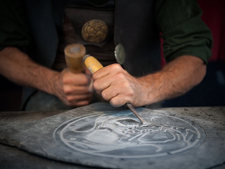 Steinmetze und Steinbildhauer Handwerker arbeitet mit Hammer und Meißel an einer Steingravur