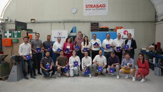 Junghandwerker Gruppenfoto von 19 Personen mit blauen Taschen in einer Werkstatt