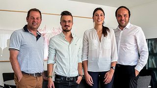 Junghandwerker Vier Personen in Büro mit legerer und formeller Kleidung posieren für Gruppenfoto